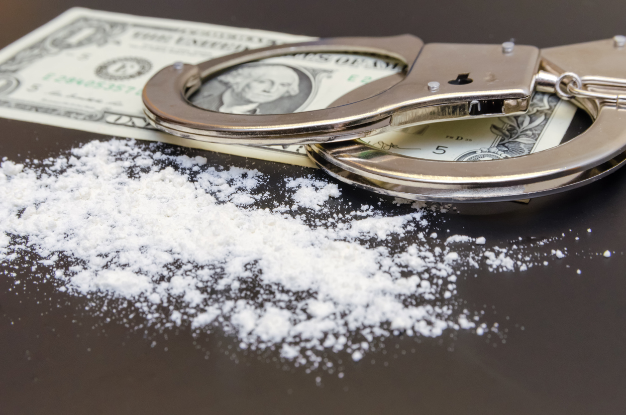 Handcuffs, money and cocaine drugs on black background close up