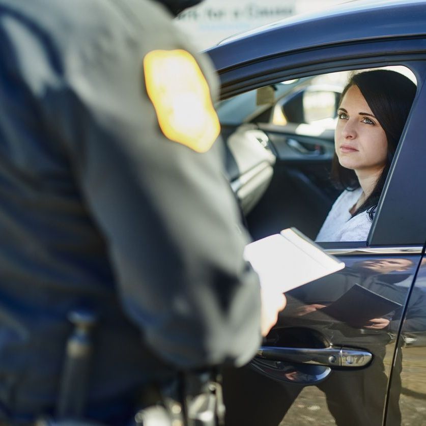 Cropped shot of an unrecognizable male traffic officer issuing a ticket to a female civilian at a roadblock