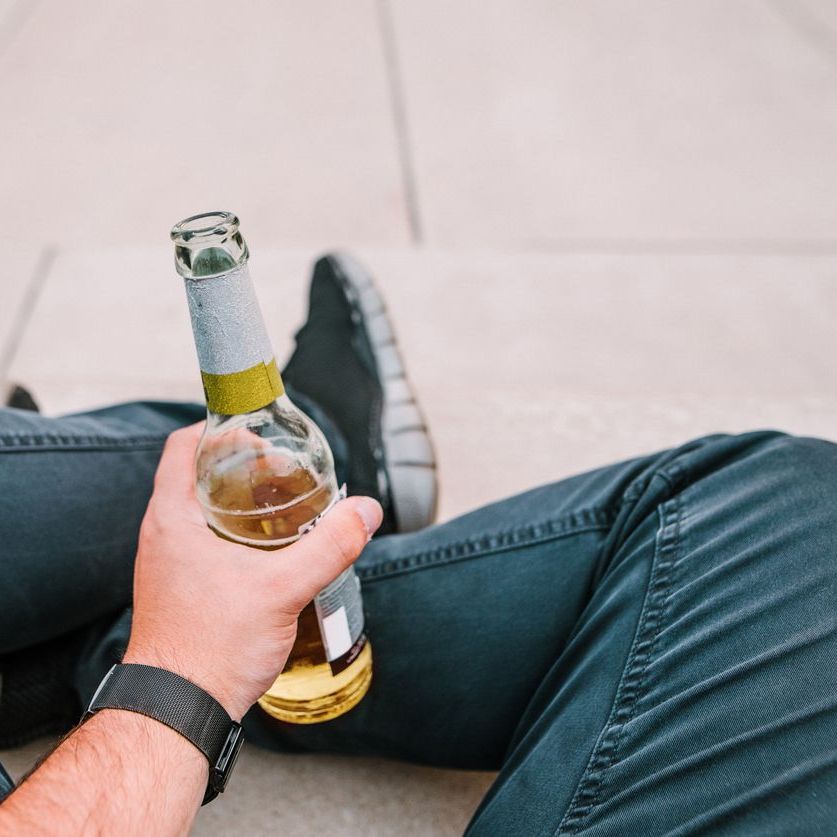 Detail of a young man holding a beer bottle