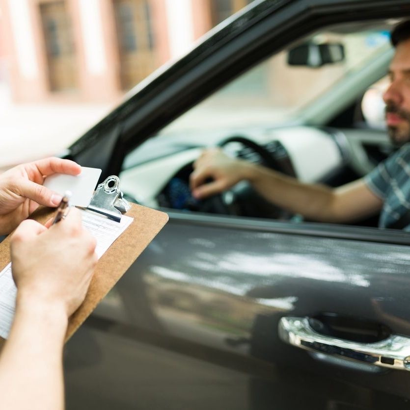 Close up of a police cop writing a traffic ticket or fine to a male driver in his car for speeding